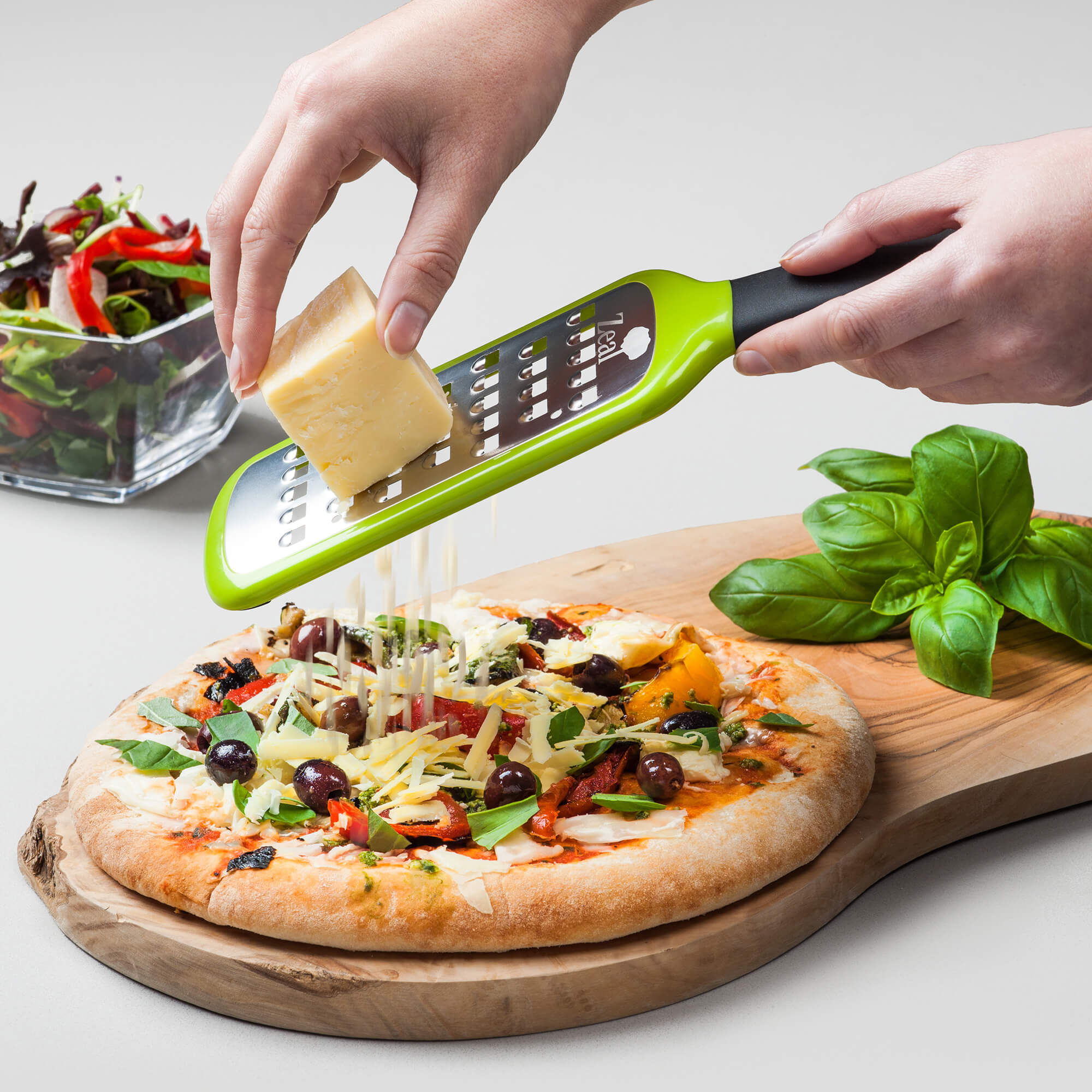 Hard cheese being grated over a pizza using a Zeal Coarse Grater