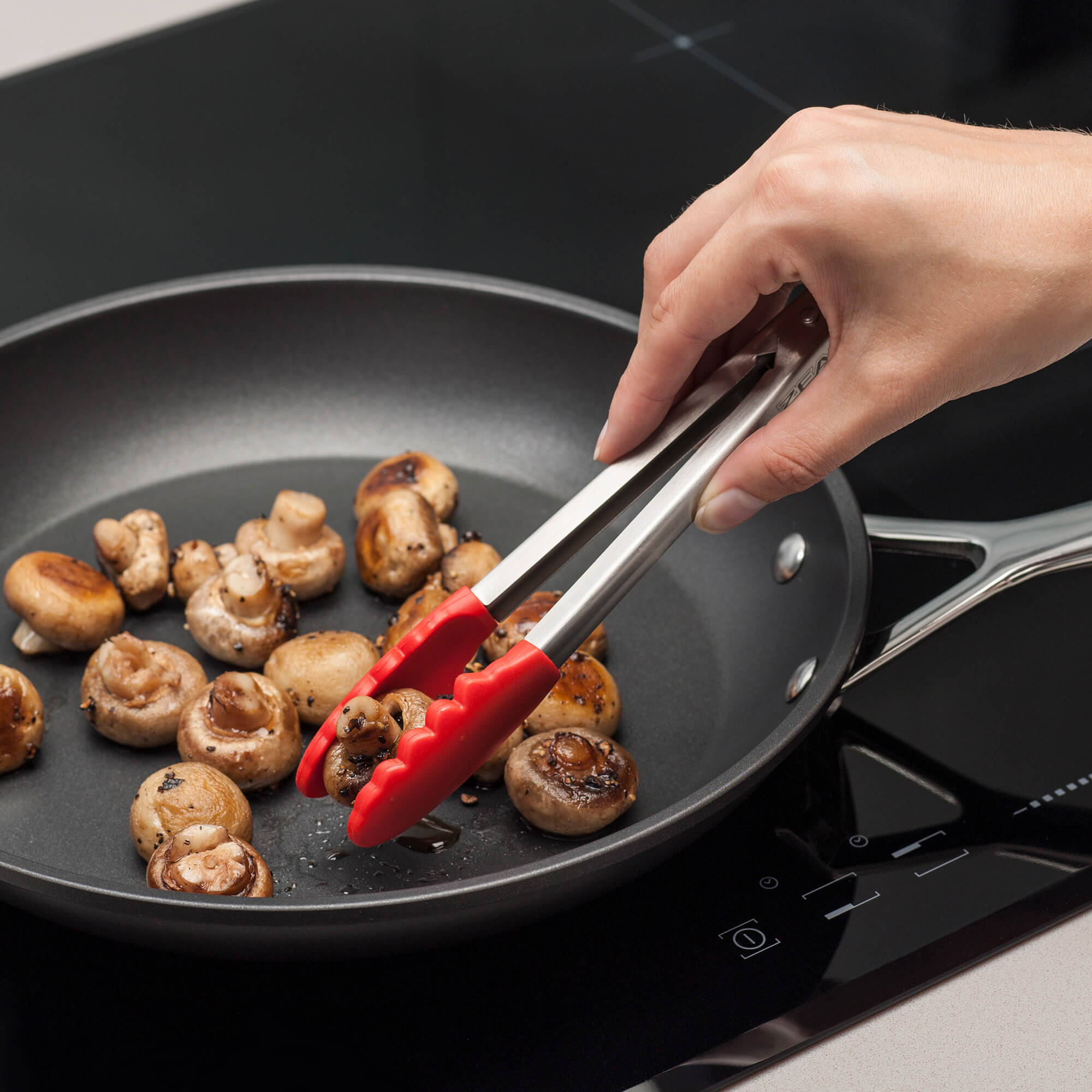 Zeal Silicone Mini Tong turning mushrooms in a pan