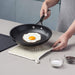 Silicone Square Shaped Hot Mat and Grab used as a trivet under fried eggs