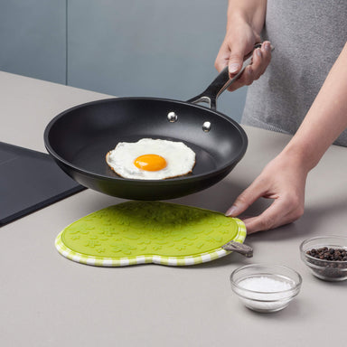 Silicone Heart Shaped Hot Mat and Grab used as a trivet under fried eggs